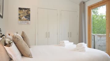 Un dormitorio con cama, almohadas, un cartel y una ventana.