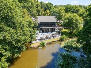 A riverside building with outdoor seating and a deck overlooking the water. - 11 Water's Edge (Looe)