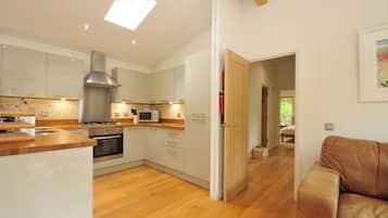 A modern kitchen with wooden flooring, a built-in oven, and a microwave.