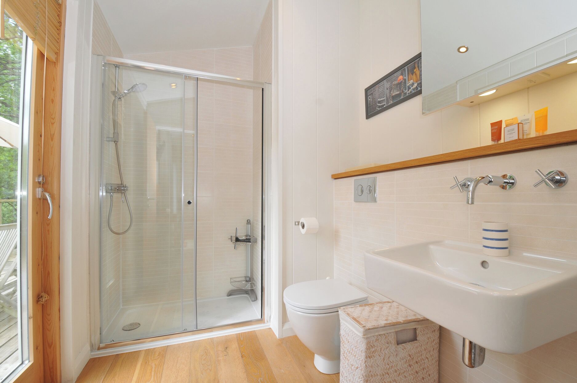 A bathroom with a glass-enclosed shower, a white toilet, and a sink with a mirror above.
