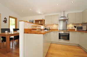 A modern kitchen with wooden countertops, a stainless steel range hood, and built-in appliances. - 11 Water's Edge (Looe)
