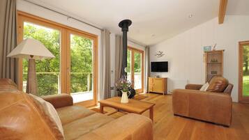 A spacious living room with leather sofas, a wooden coffee table, a TV, and a fireplace.