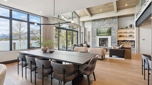 A spacious living area with a stone fireplace, a dining table with chairs, and a view of a lake.