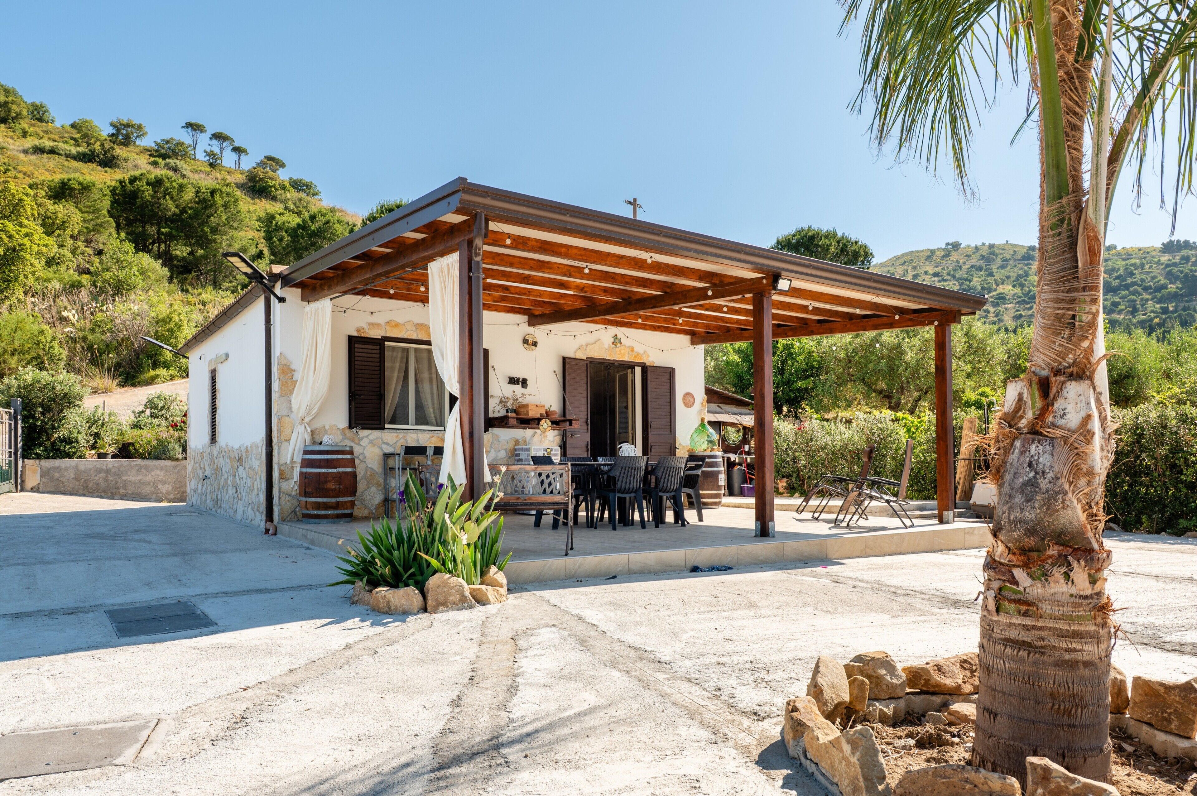 A house with a covered patio, outdoor seating, and a stone wall.