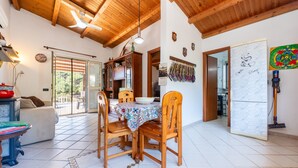 A dining area with wooden chairs, a table with a patterned tablecloth, a ceiling fan, and a refrigerator. - Casa Villa Aury — Cefalù, green oasis steps from the sea (Cefalù)