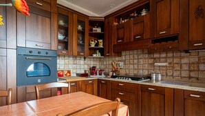A kitchen with wooden cabinets, a built-in oven, a dining table with chairs, and a tiled backsplash.