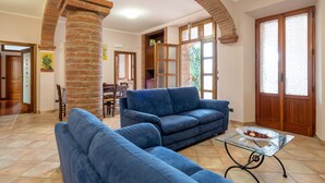 A living room with a blue sofa, a glass coffee table, and a brick column.
