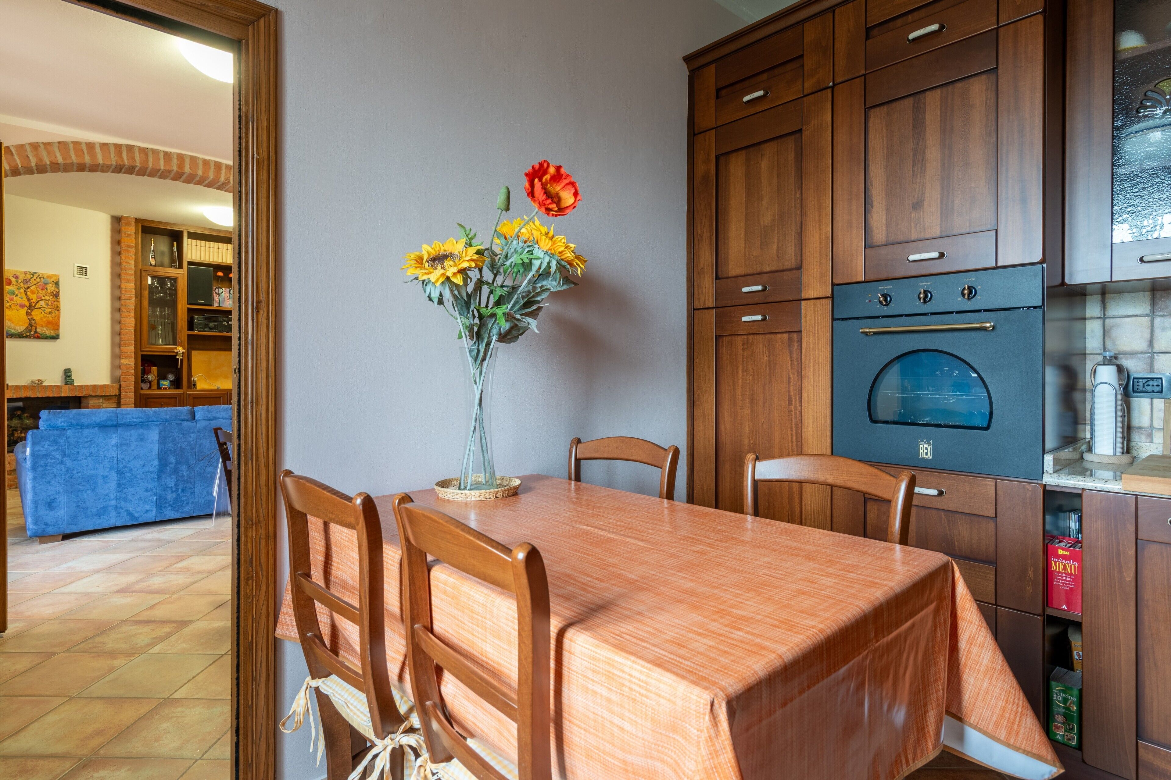 Een eethoek met een houten tafel, stoelen en een vaas met bloemen.