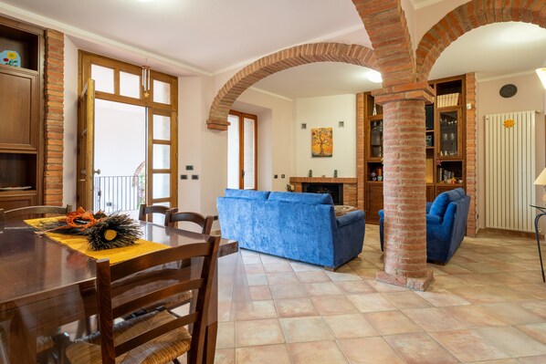 Un comedor con una mesa y sillas de madera, un sofá azul y una chimenea de ladrillo.