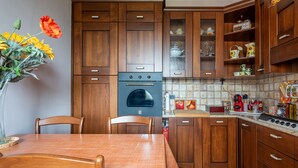 A kitchen with wooden cabinets, a stove, and a dining table with chairs.