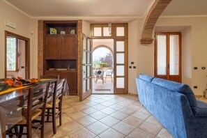 A dining area with a wooden table and chairs, a blue sofa, and a view of an outdoor patio.