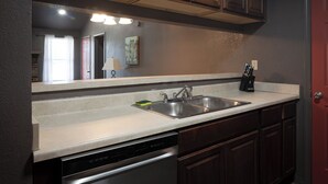 A kitchen with a dishwasher, double sink, and wooden cabinets.