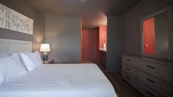 A bedroom with a bed, nightstand, dresser, and a mirror.