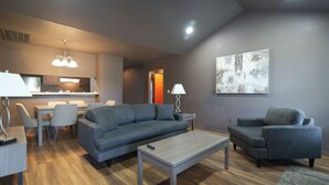 A modern living room with a sofa, armchair, coffee table, and dining area.