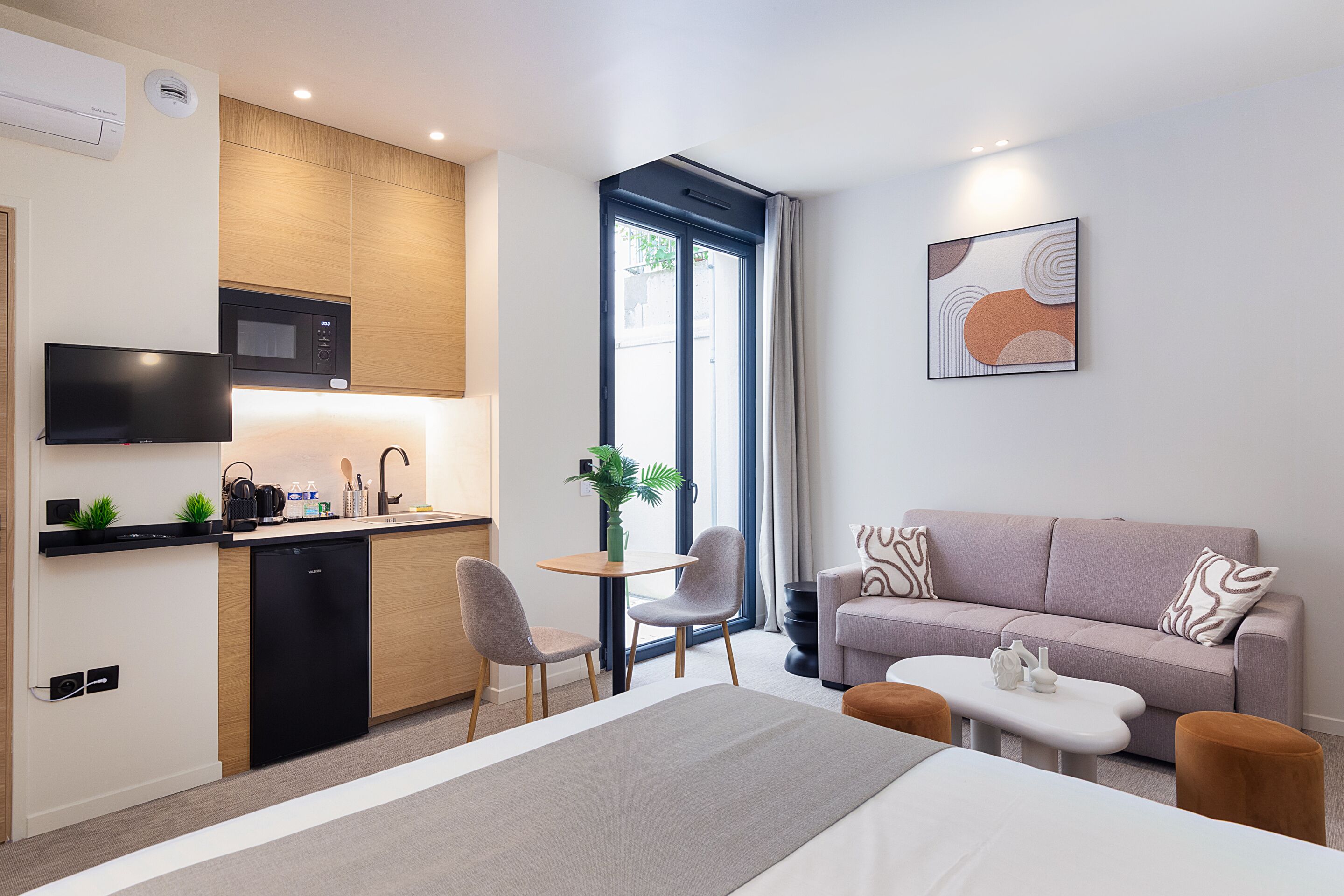 A compact living space with a kitchenette, a sofa, a dining table, and a TV.
