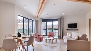 A modern living room with a dining area, large windows, and a flat-screen TV. - Maison Solférino  (Boulogne-Billancourt)