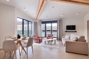 Una sala de estar moderna con comedor, ventanas grandes y un televisor de pantalla plana.