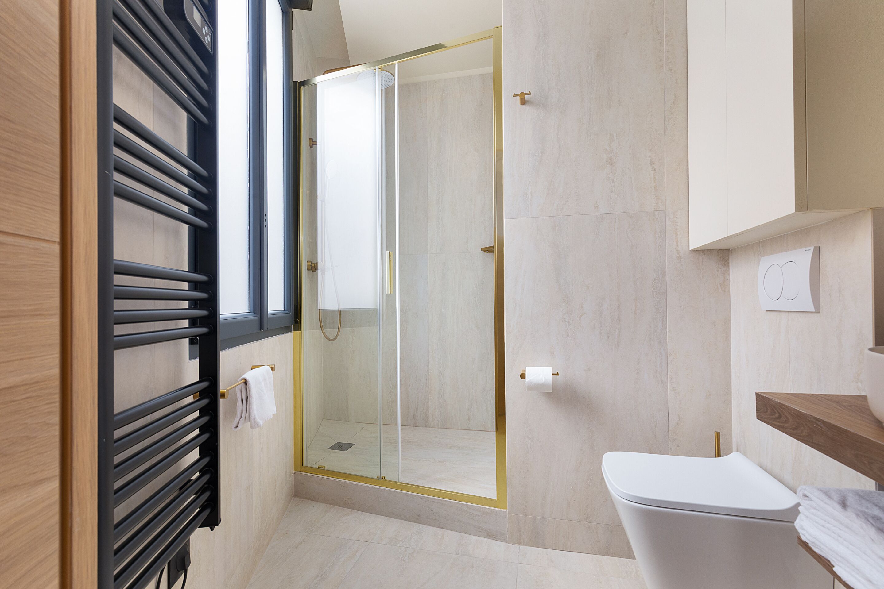 A modern bathroom with a glass shower enclosure, a toilet, and a towel rack.