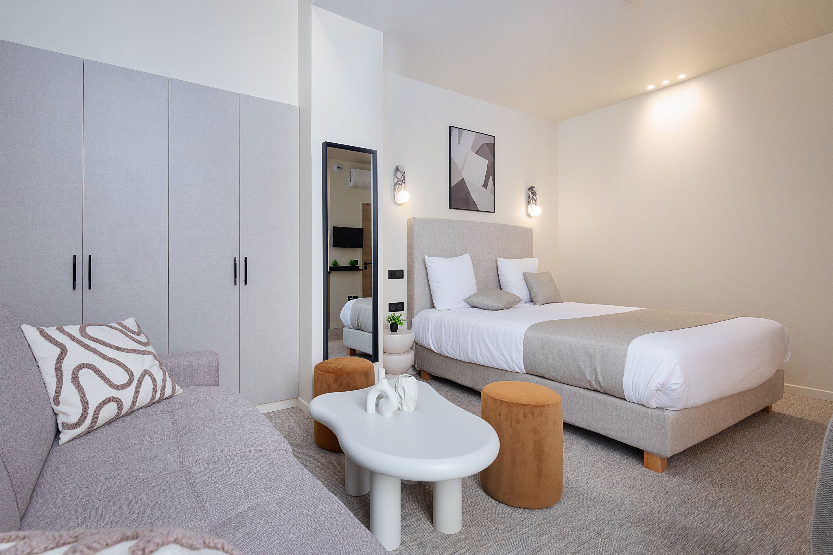 A modern bedroom with a bed, a sofa, a small table, and a wardrobe.