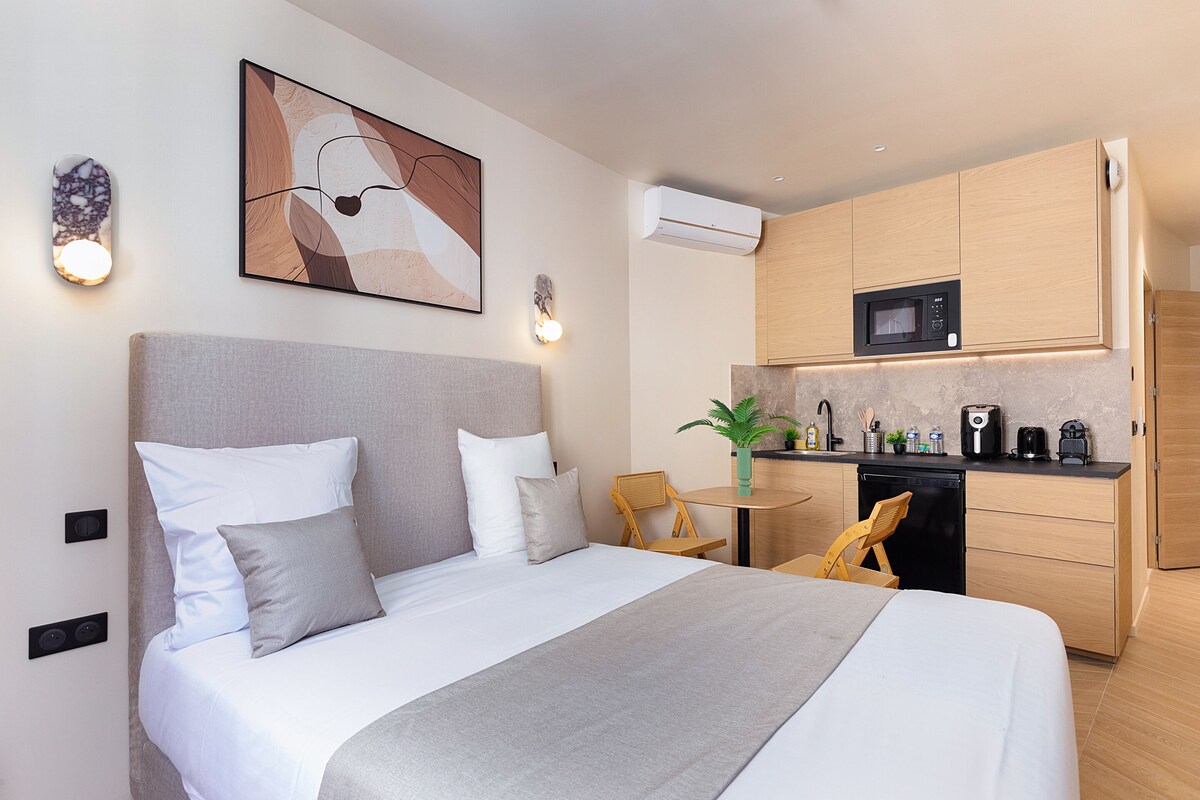 Una habitación de hotel moderna con cama, una pequeña cocina y una mesa de comedor.