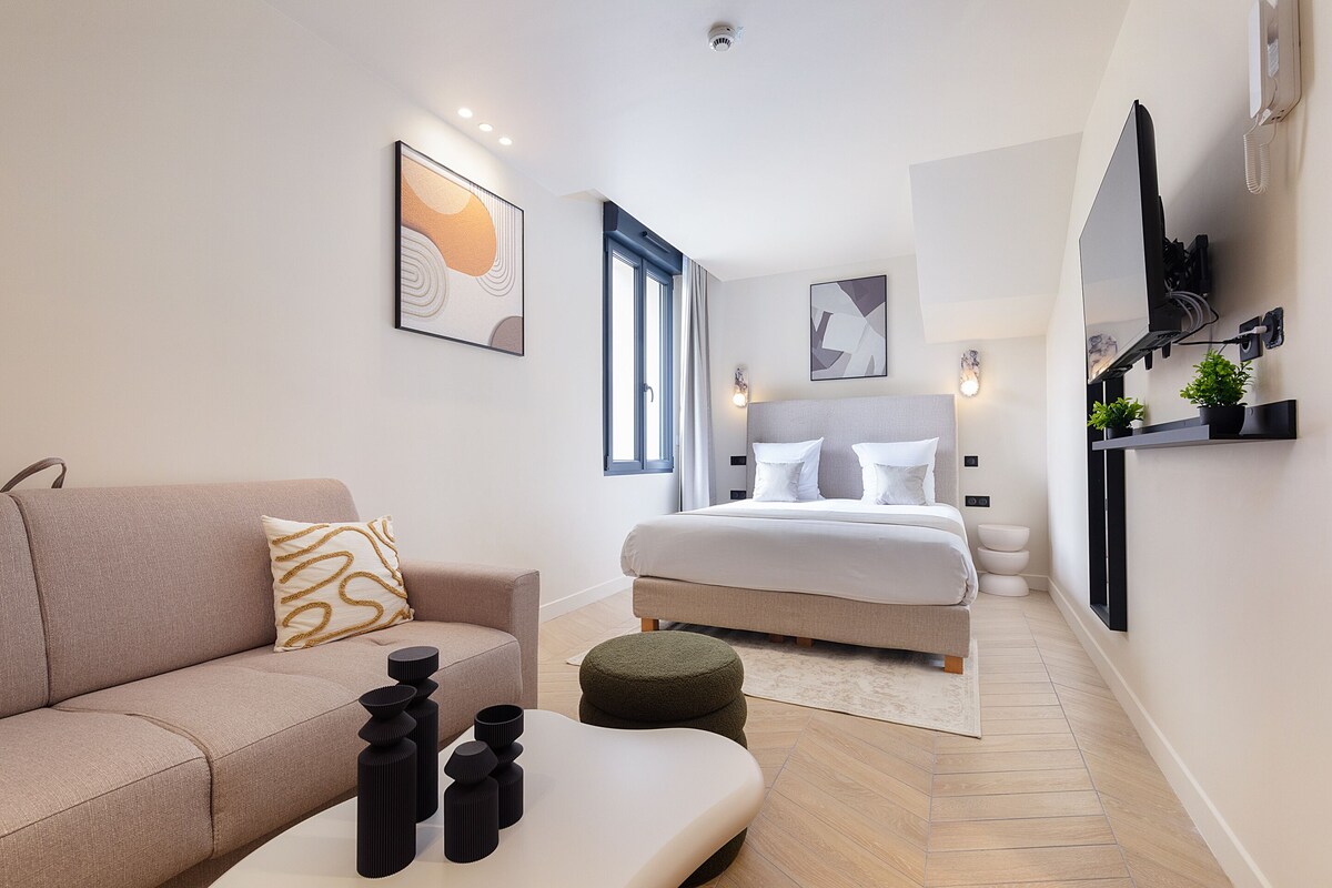 Una habitación de hotel moderna con una cama, un sofá, una mesita de café y adornos en la pared.