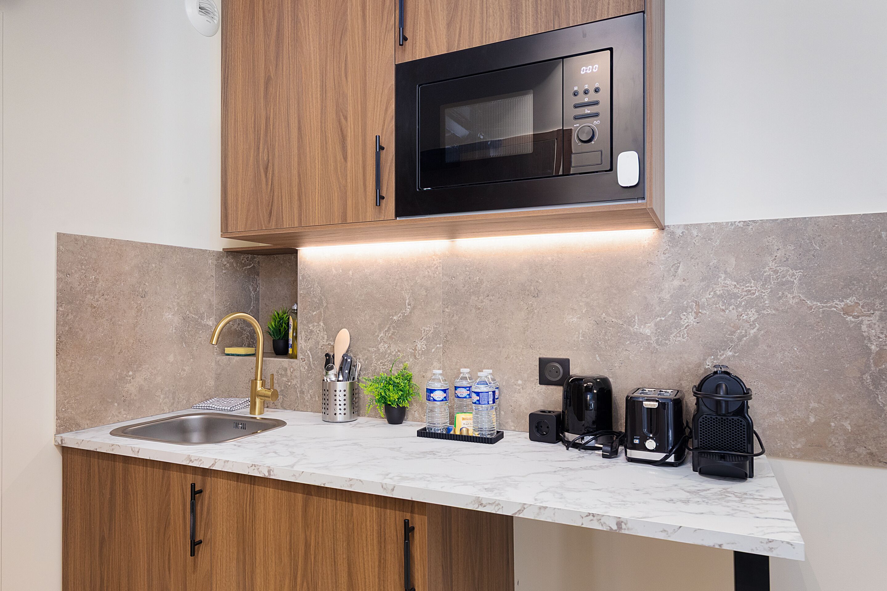 A kitchen with a built-in microwave, a sink, and various appliances.