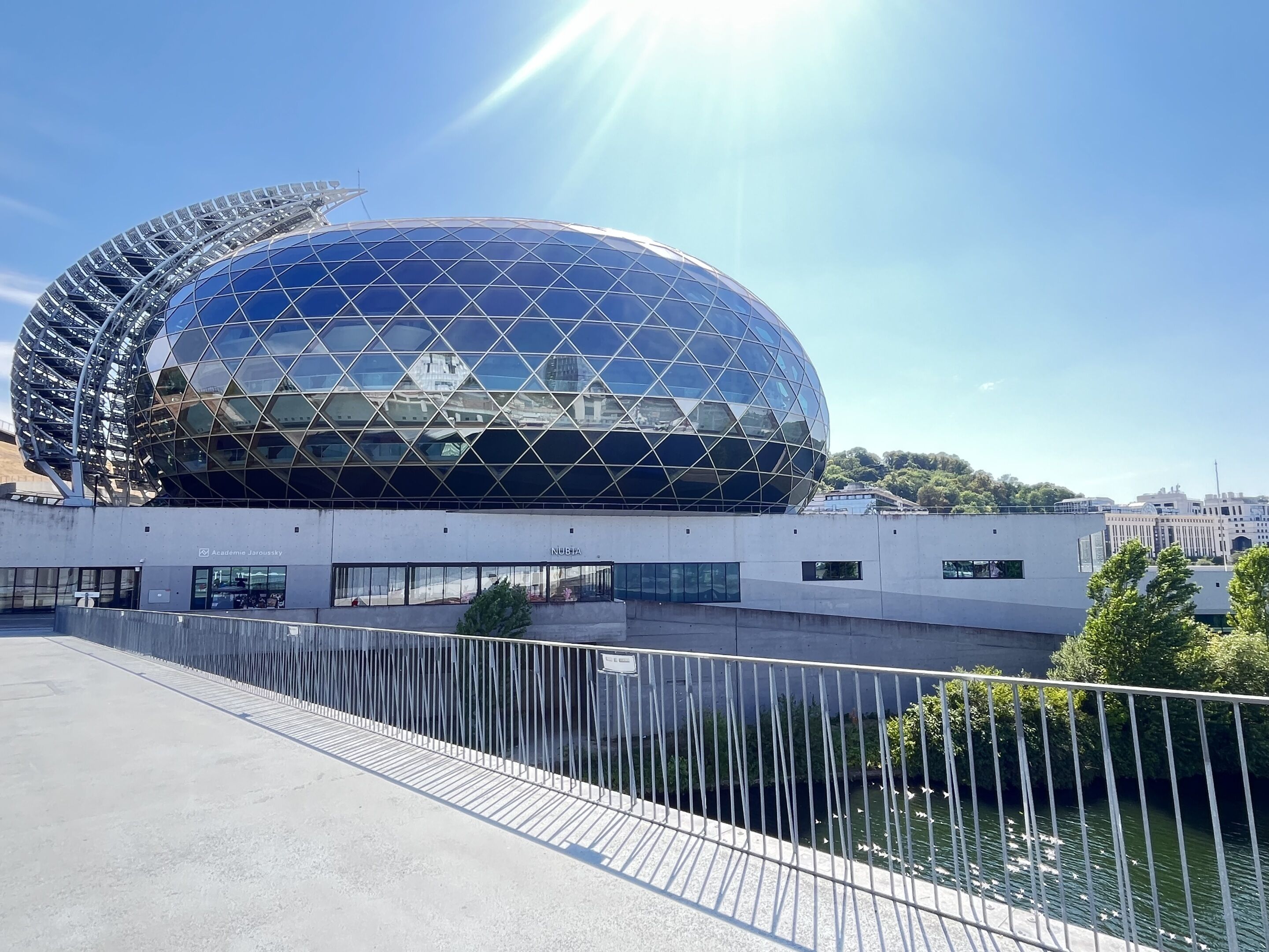Um edifício moderno com fachada de vidro esférico e estrutura metálica.