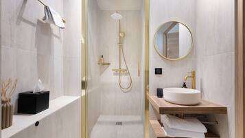A modern bathroom with a glass-enclosed shower, a round mirror, a sink, and a towel rack.