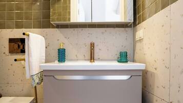 A bathroom with a white vanity, a towel rack, a glass shower enclosure, and a toilet.