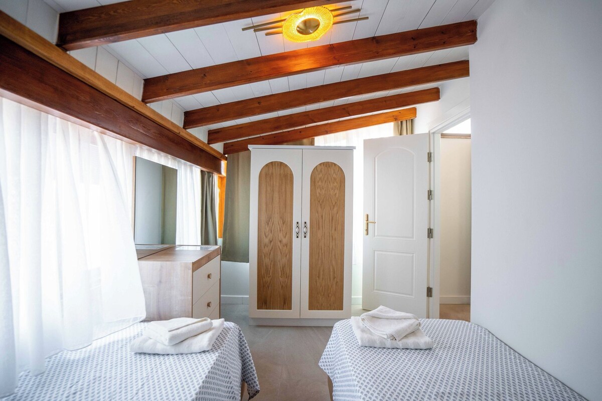 A bedroom with two beds, a wardrobe, and a mirror.