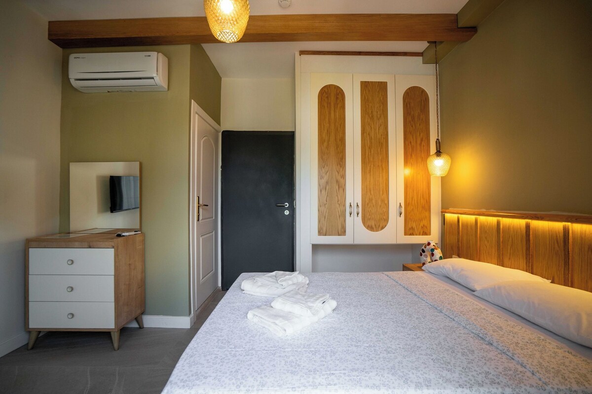 A hotel room with a bed, a dresser, a wardrobe, and a television.
