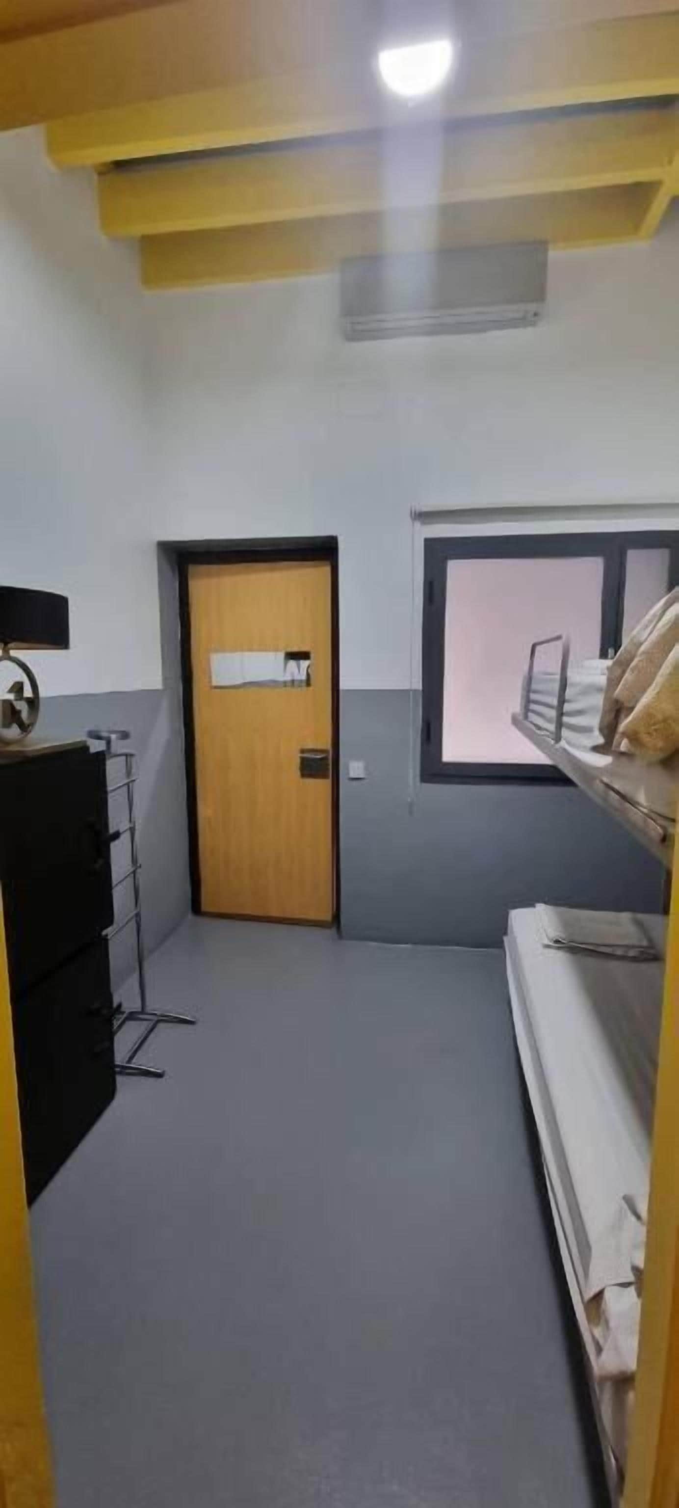 Une pièce avec une porte, une fenêtre, un lit, un bureau et une chaise.