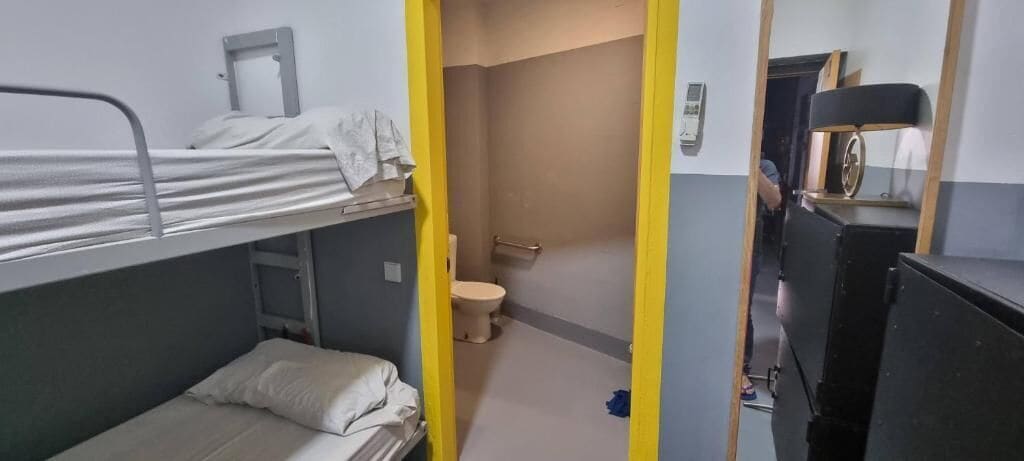 Camera con letto a castello, servizi igienici e una scrivania.