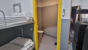 Ein Schlafraum mit Etagenbett, Toilette und Schreibtisch.