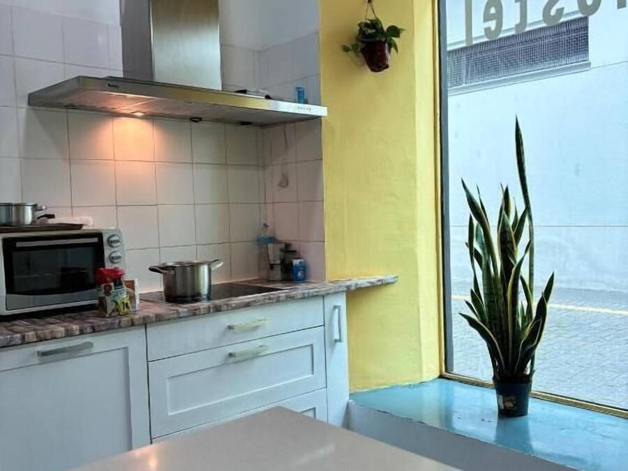 Una cocina con armarios blancos, una campana extractora de acero inoxidable, un microondas y una ventana con vistas.