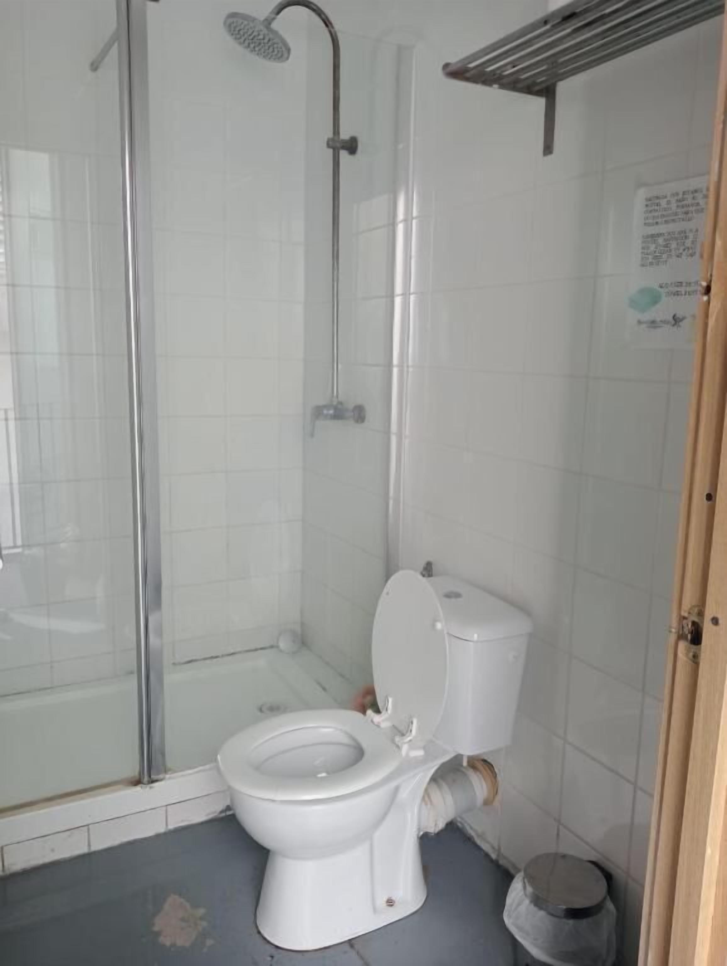 Un baño con ducha, inodoro y un cubo de basura.