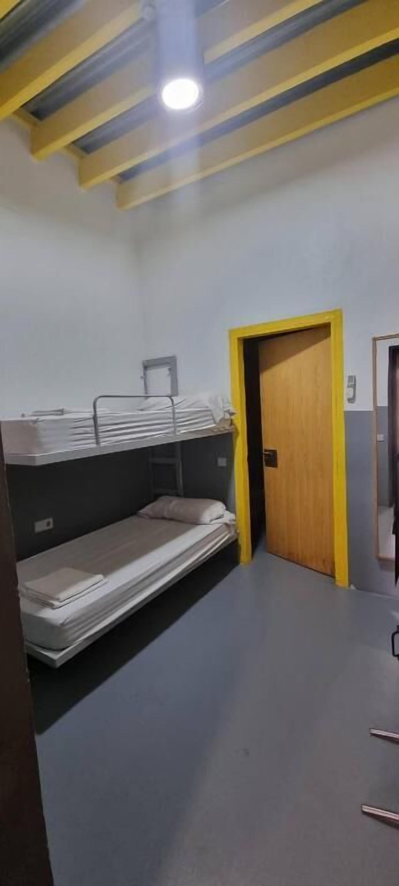Una habitación con literas, una puerta de madera y una lámpara en el techo.