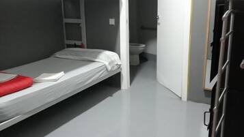 Habitación con literas y una puerta que da a un baño.