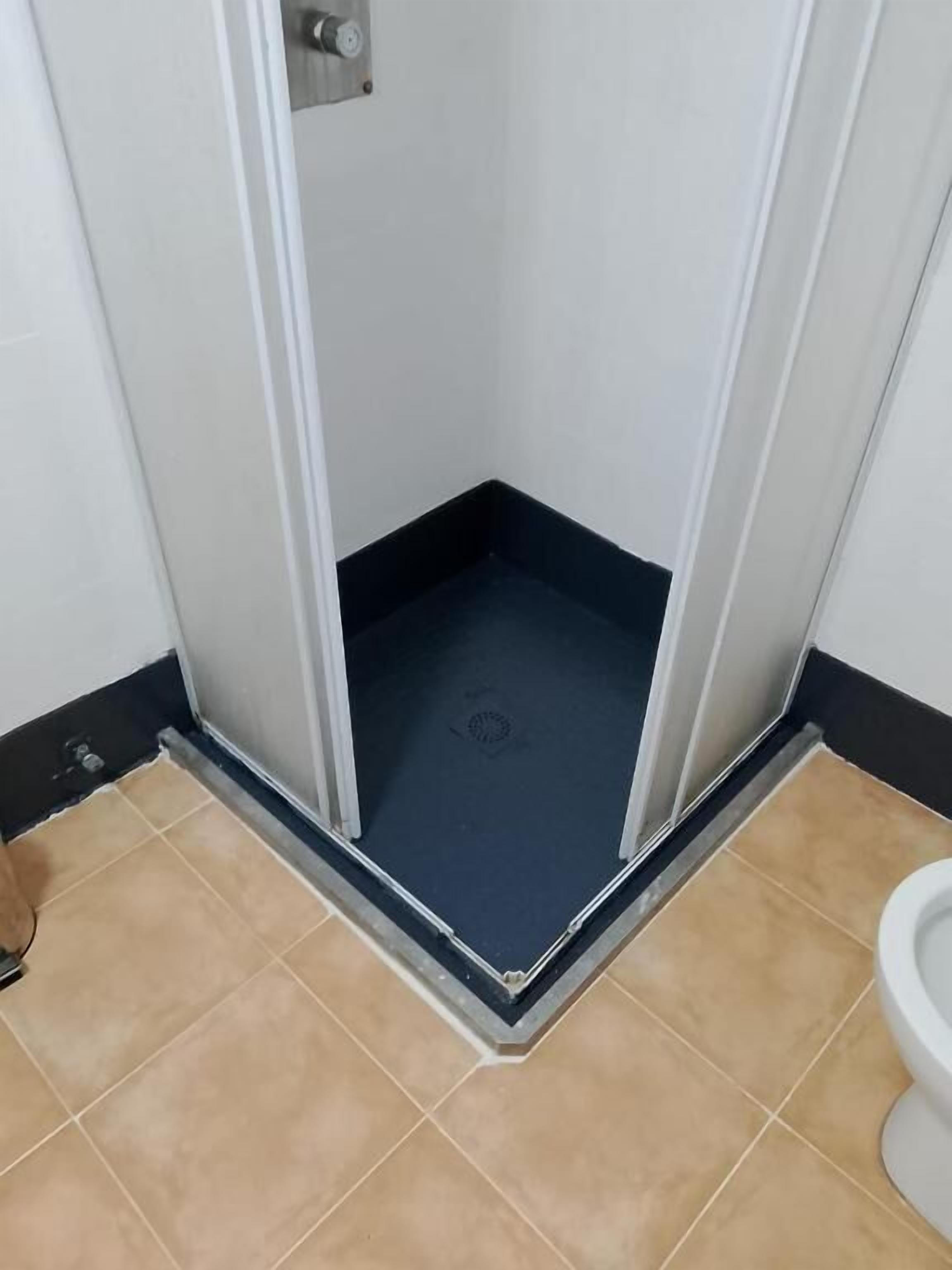 Ein Badezimmerteil mit Dusche, Toilette und gefliestem Boden.