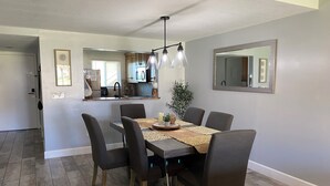 Un espace repas avec une table, des chaises et une cuisine en arrière-plan.