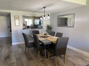 A dining area with a table, chairs, and a kitchen in the background. - Beautiful 2br 2ba Ocean View Flat! Amazing Views and Location (St Augustine)
