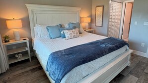 Une chambre à coucher avec un lit, un ventilateur de plafond, une table de chevet, une lampe et une porte.