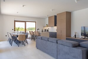 Eine moderne Küche mit Essbereich, ein großes graues Sofa und ein Fernseher.