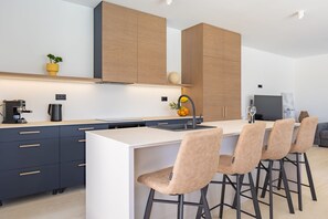 Eine moderne Küche mit einer zentralen Kochinsel, Barhocker und integrierten Schränken.