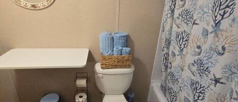 Ein Badezimmer mit Toilette, Waschbecken, Spiegel und Duschvorhang.
