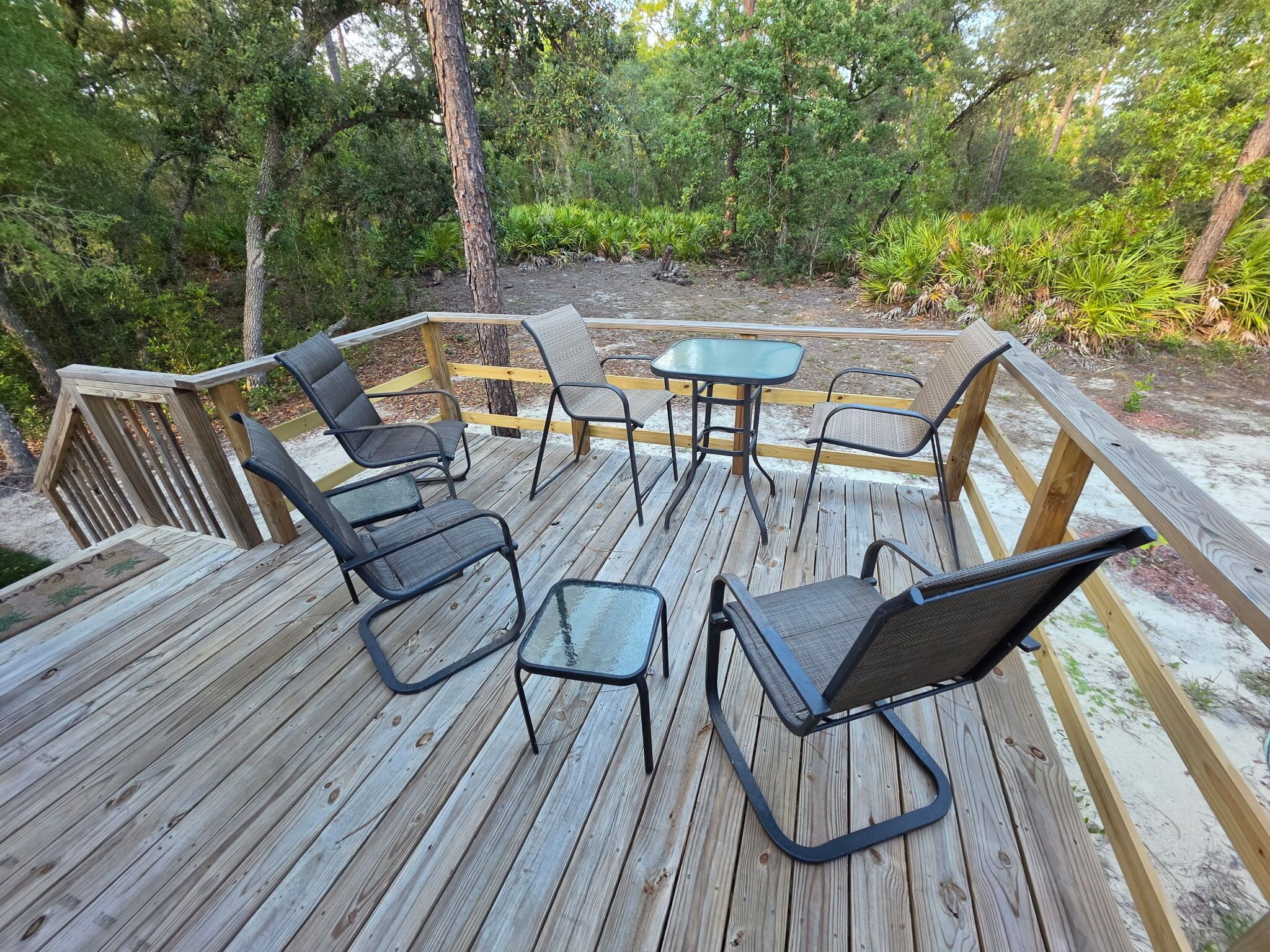 En træterrasse med havemøbler, herunder stole og et bord.