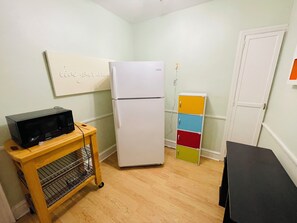A compact kitchen with a microwave, refrigerator, and a small cabinet.