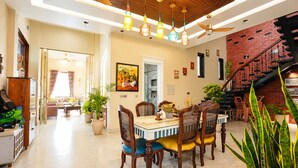 A spacious dining area with a marble table, wooden chairs, and hanging pendant lights. - The Heritage Nest Koyla Kund (Darbhanga)