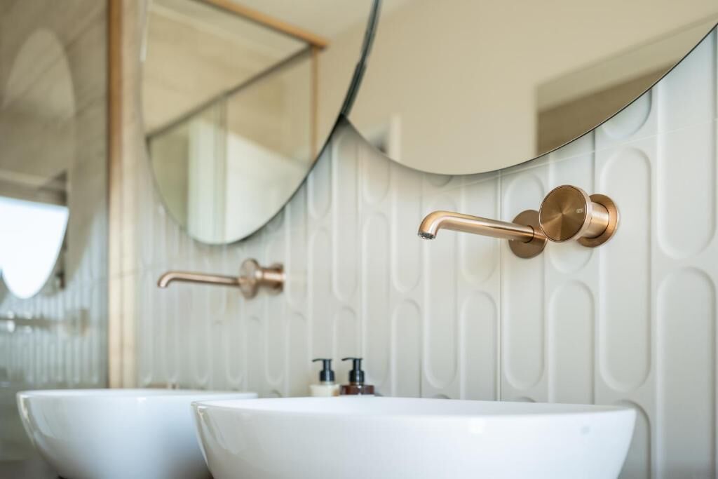 Un baño con dos lavamanos, un espejo y un grifo de pared.