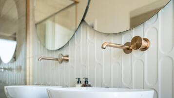 Un baño con dos lavamanos, un espejo y un grifo de pared.